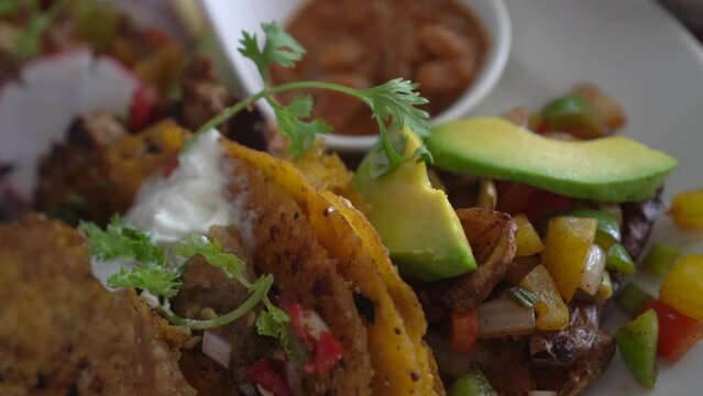 Mexican food corn tortilla hard shell taco with grilled beef salsa salad and avocado side with beans