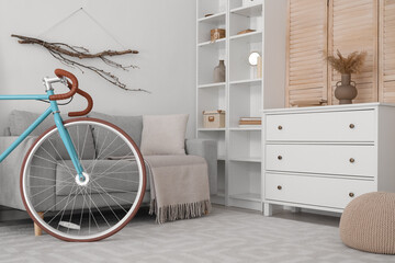 Interior of modern living room with bicycle, sofa and chest of drawers