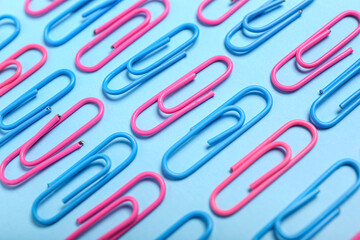 Pink and blue paper clips on color background, closeup