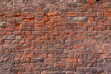 Obraz premium Old exterior European brick wall texture background in an English bond brickwork pattern, with weathered bricks in varying shades of red