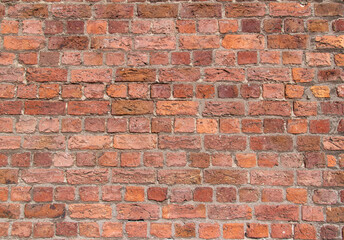Old exterior European brick wall texture background in an English bond brickwork pattern, with weathered bricks in varying shades of red