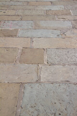 Close up view of a beige color grungy European stone walkway texture background, with large rectangular shaped paving bricks of different sizes and dimensions