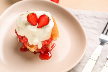 Plate with strawberry cinnamon roll and cream on beige background, closeup