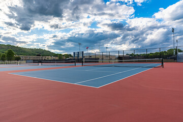 New blue tennis courts with white lines and red out of play area.	