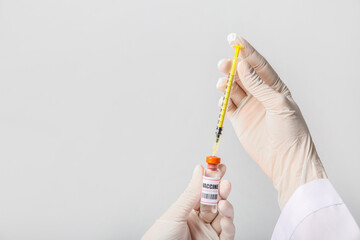 Female doctor with monkeypox vaccine and syringe on grey background