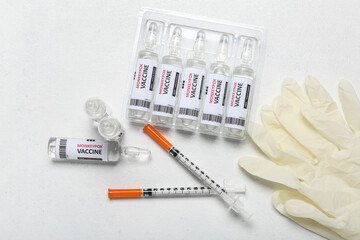 Ampules of monkeypox vaccine with syringes and gloves on white background