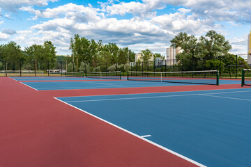 New blue tennis courts with white lines and red out of play area.	