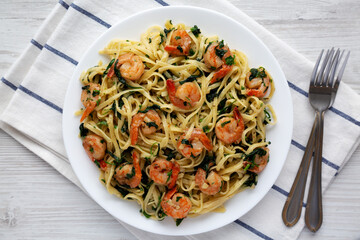 Homemade One-Pot Lemon Garlic Shrimp Pasta on a Plate on a white wooden surface, top view. Flat lay, overhead, from above.
