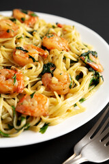 Homemade One-Pot Lemon Garlic Shrimp Pasta on a Plate on a black background, side view.