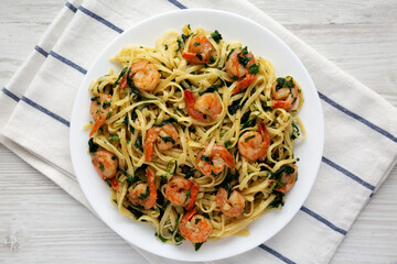 Homemade One-Pot Lemon Garlic Shrimp Pasta on a Plate on a white wooden surface, top view. Flat lay, overhead, from above.