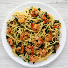 Homemade One-Pot Lemon Garlic Shrimp Pasta on a Plate on a white wooden background, top view. Flat lay, overhead, from above.