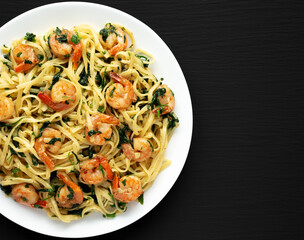 Homemade One-Pot Lemon Garlic Shrimp Pasta on a Plate on a black background, top view. Copy space.