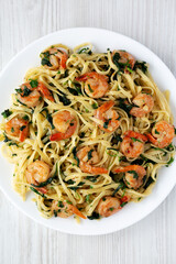 Homemade One-Pot Lemon Garlic Shrimp Pasta on a Plate on a white wooden surface, top view. Flat lay, overhead, from above.