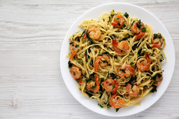 Homemade One-Pot Lemon Garlic Shrimp Pasta on a Plate on a white wooden background, top view. Flat lay, overhead, from above. Copy space.
