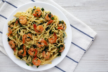 Homemade One-Pot Lemon Garlic Shrimp Pasta on a Plate on a white wooden surface, top view. Flat lay, overhead, from above. Copy space.