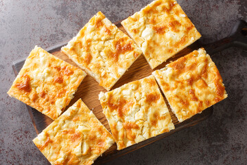 Alevropita crispy feta pie is a specialty of Epirus close-up on a wooden board on the table. Horizontal top view from above