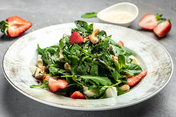 Strawberry salad with spinach, nuts, cheese, Fresh vegetarian salad on gray stone background, Food recipe background. Close up