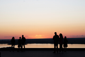 Silhouettes of people against the background of a pink orange sunset