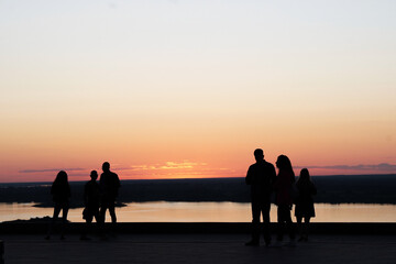 Fototapeta premium Silhouettes of people against the background of a pink orange sunset