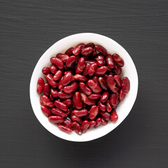 Red Organic Kidney Beans in a White Bowl on a black background, top view. Flat lay, overhead, from above.