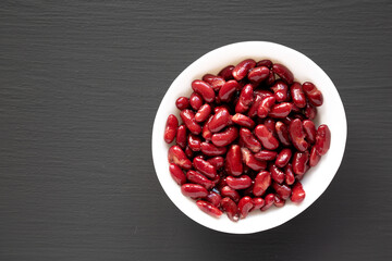 Red Organic Kidney Beans in a White Bowl on a black background, top view. Flat lay, overhead, from above. Copy space.