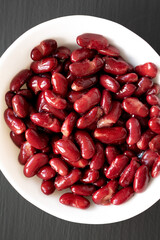 Red Organic Kidney Beans in a White Bowl on a black background, top view. Flat lay, overhead, from above.