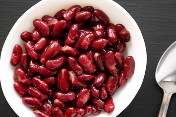 Red Organic Kidney Beans in a White Bowl on a black background, top view. Flat lay, overhead, from above.