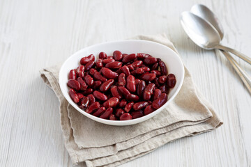 Red Organic Kidney Beans in a White Bowl on a white wooden background, top view. Flat lay, overhead, from above.
