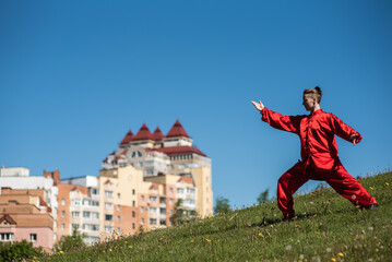 Asian woman in red kimano practicing taijiquan outdoors, chinese martial arts, healthy lifestyle concept.
