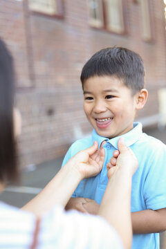 A mother fixing her son's school shirt collar