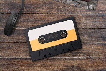 Vintage audio cassette between headphones and personal cassette player on a surface