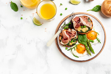 Traditional full English breakfast with grilled bun with spinach and cheese, asparagus, jamon, ham, prosciutto and fried egg. fresh juice. Balanced diet. top view