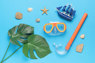 A set for swimming underwater, large leaves and a ship figurine on a blue background. Minimal...