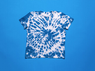 White and blue tie dye T-shirt on a blue background. Flat lay.