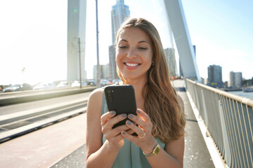 Portret van jonge ondernemer die smartphone gebruikt op moderne brug in Rotterdam, Nederland