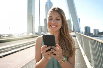 Foto op Plexiglas Erasmusbrug Portret van jonge ondernemer die smartphone gebruikt op moderne brug in Rotterdam, Nederland