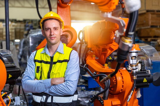 Portrait smart engineer man working with advance robotic machine weling in heavy industry.