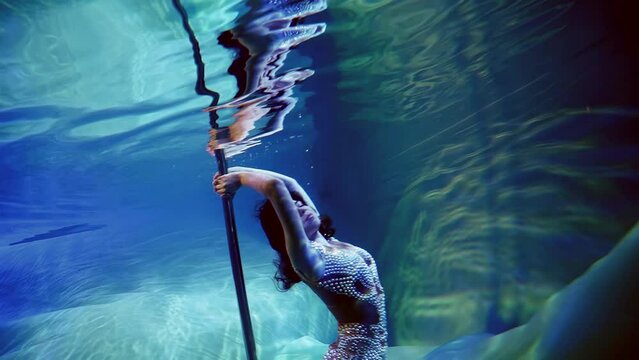 seductive woman is floating underwater, dancing slowly with pylon, erotic fantasy and dream