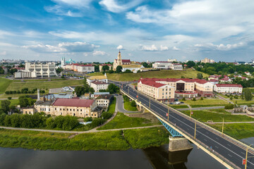 aerial view from great height on red roofs of old city with heavy traffic on bridge with wide multi-lane road across wide river