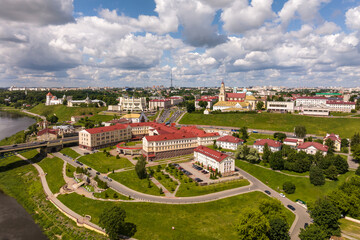 aerial view from great height on red roofs of old city with heavy traffic on bridge with wide multi-lane road across wide river