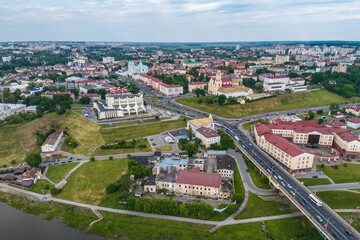 Fototapeta na wymiar aerial view from great height on red roofs of old city with heavy traffic on bridge with wide multi-lane road across wide river