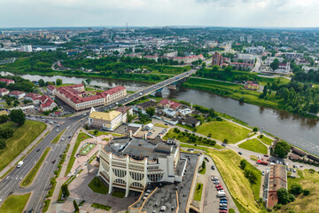 aerial view from great height on red roofs of old city with heavy traffic on bridge with wide multi-lane road across wide river