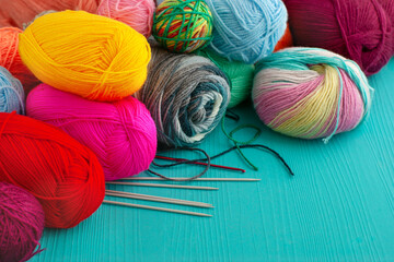 Beautiful bright yarn for knitting close-up. A lot of multi-colored yarn on a turquoise background. Knitting is a type of needlework. There is space for text.