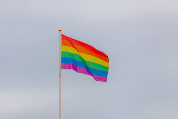 Celebration of pride month, Colourful flags hanging on the pole in cloudy sky background, The rainbow flag is a symbol of lesbian, gay, bisexual, transgender and queer, World LGBTQ social movements.