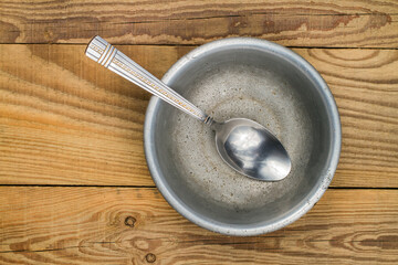 Aluminum bowl with a spoon on the background of wood.