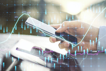 Close up of hands using tablet and smartphone at desktop with abstract glowing forex graph on...