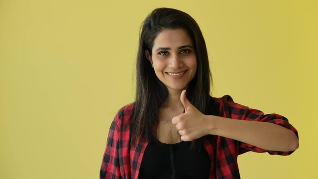 Close-up portrait of young Indian smiling girl in studio happy satisfied woman showing thumb up looking at camera giving positive service female client feeling satisfied approval symbol.