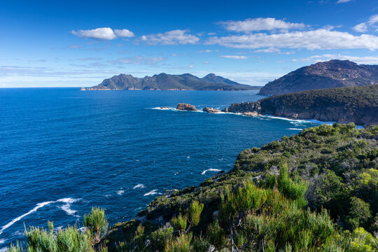 View over ocean and mountains with blue sky and clouds at Freycinet Peninsula