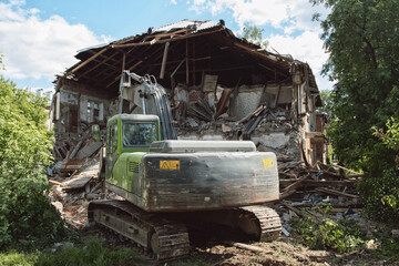 Fototapeta na wymiar Powerful crawler excavator demolishes an old building