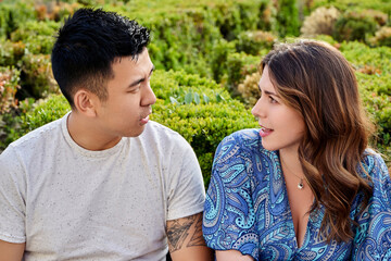 Fototapeta premium Two friends talking while sitting on a bench in a park outdoors. Friendship concept.